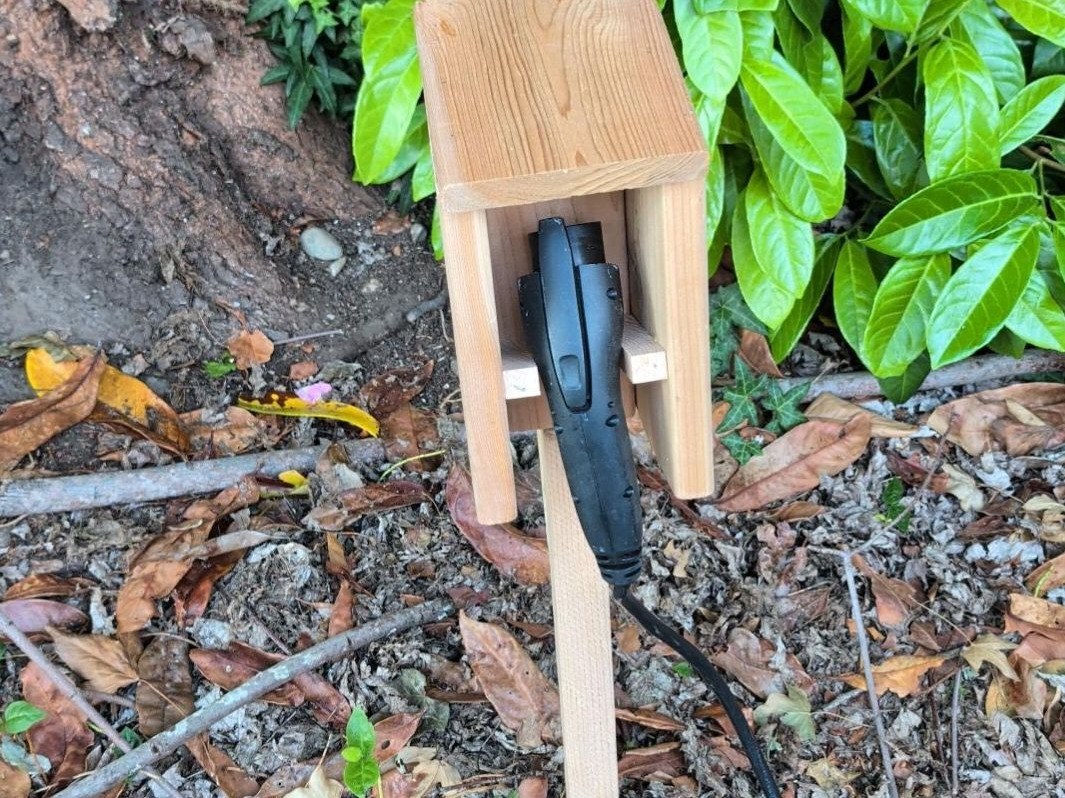 EV charge handle holder — Cedar, capped cradle staked by the drive